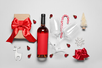 Bottle of wine with glasses, Christmas toys and gifts on grey background