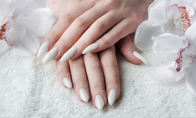 Hands of a young woman with white manicure on nails