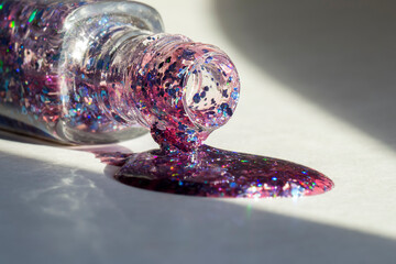 Glitter nail polish pouring from a bottle onto a surface