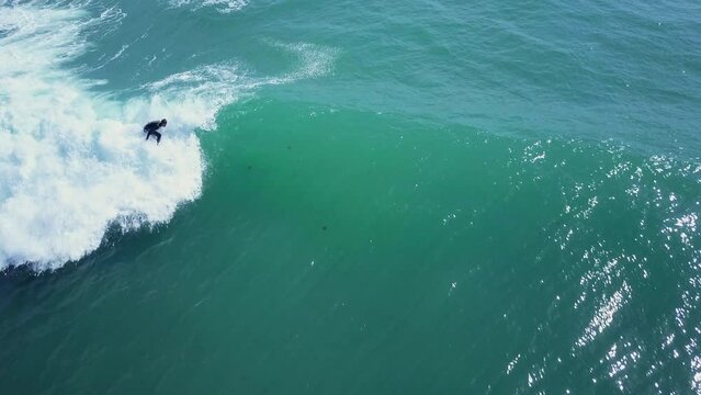 overhead drone shoot of surfer riding waves over Ca&ntilde;os de Meca beach in Cadiz ,Spain where the drone glides shows us the sea with the surfers in turns over waves during a sunny summer day