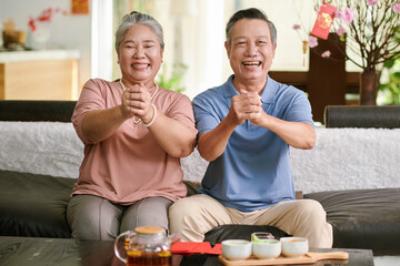 Happy senior man and woman making greeting gesture and smiling at camera