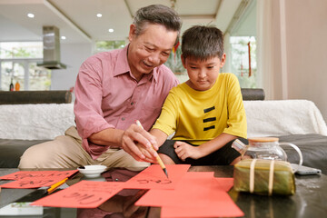 Grandfather teaching grandson calligraphy for Tet celebration