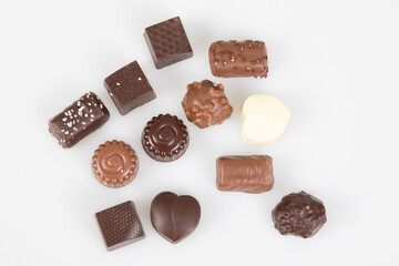 some fine dark and milk chocolate in different shapes pralines in top view in white background