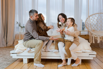 Happy family when mom and dad spend time at home together with two children. Parents play in bed. Relationships in the family