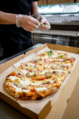 cook cutting pizza to pieces at pizzeria