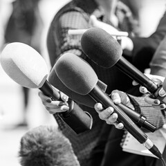 News reporters interviewing an unrecognizable people outdoors