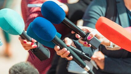 News reporters interviewing an unrecognizable people outdoors