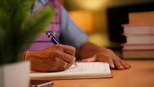 Close up shot of man hands writing personal diary at midnight at home - concept of hobbies, routine lifestyle and knowledge.