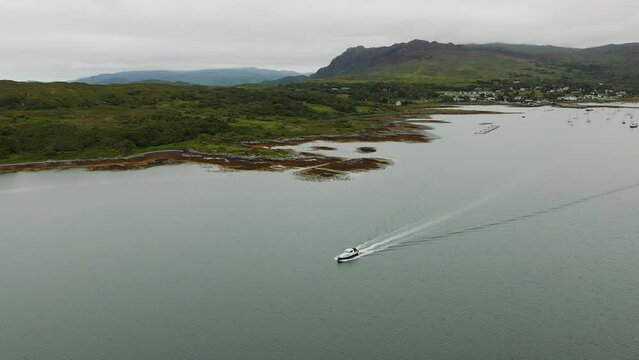 Cinematic aerial angle panning around boat cruising away from Arisaig Harbour on the West Coast of Scotland