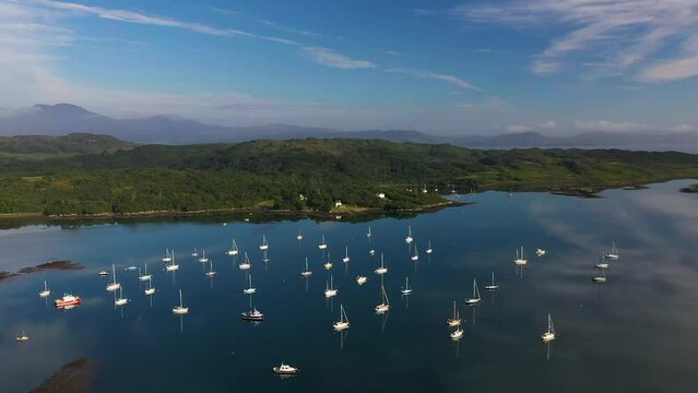 4K aerial angle panning around Arisaig marina towards village. Drone shot of Arisaig bay and boats turning to reveal village on West Coast of Scotland