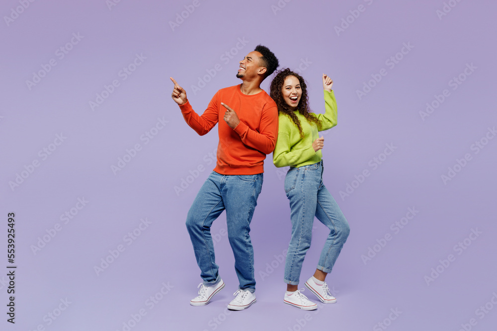 Sticker Full body sideways fun young couple two friends family man woman of African American ethnicity wear casual clothes together point finger aside on area isolated on pastel plain light purple background.