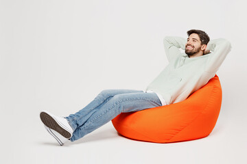 Full body young minded dreamful happy smiling man wear mint hoody sit in bag chair look camera hold...