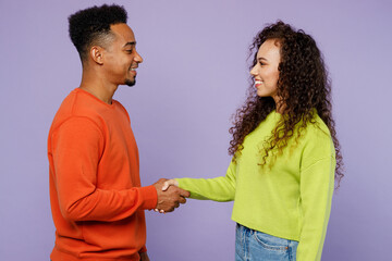 Young couple friend family man woman of African American ethnicity wear casual clothes together hold hands folded handshake gesture isolated on pastel plain light purple background Friendship concept