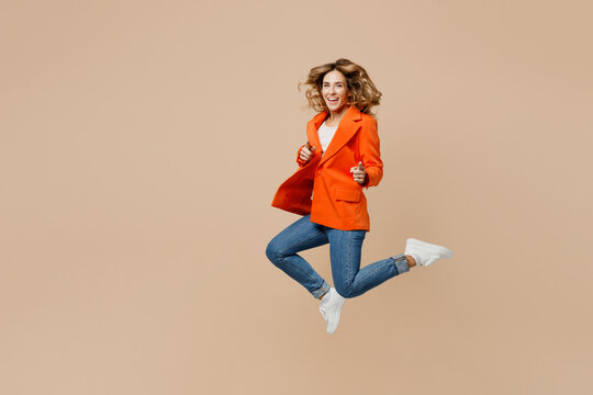 Full Body Young Employee Business Woman Corporate Lawyer Wear Formal Orange Suit Glasses Work In Office Jump High Point Index Finger Camera On You Encourage Isolated On Plain Beige Background Studio.