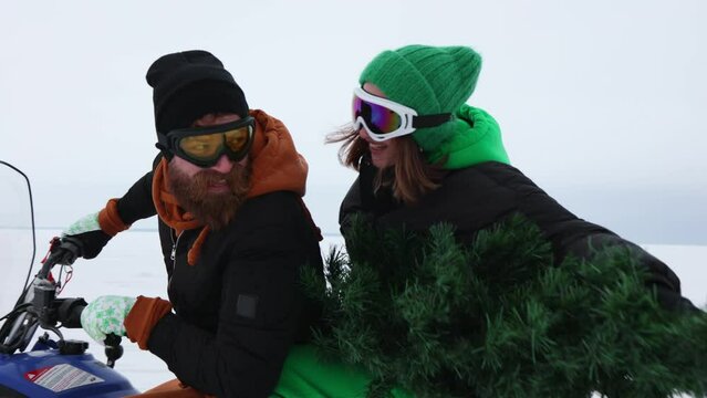 young family carries Christmas tree snowmobile through snowy field,holidays
