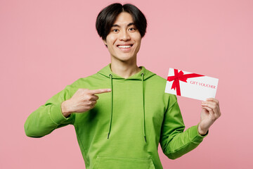 Young fun man of Asian ethnicity wear green hoody look camera hold point index finger on gift...