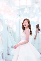 Naklejka premium Pretty asian lady turning back with smile on her wedding dress