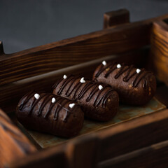 Chocolate cakes oval shape with chocolate topping, in wooden box on a dark background.