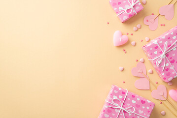 Valentine's Day concept. Top view photo of pink gift boxes paper hearts on sticks candle and sprinkles on isolated beige background with copyspace