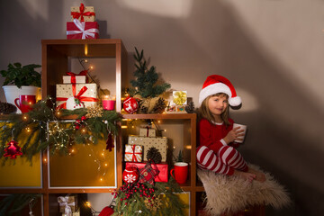 Happy New Year concept. advent calendar. Happy child drinks cocoa sitting on a dresser with gifts and Christmas decor. Happy Holidays. Winter cozy style hygge concept. 