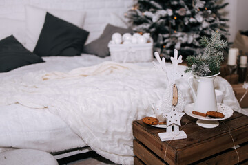 Cozy Christmas interior with bed and marshmallow in the white cup with sweets and decorations on the table