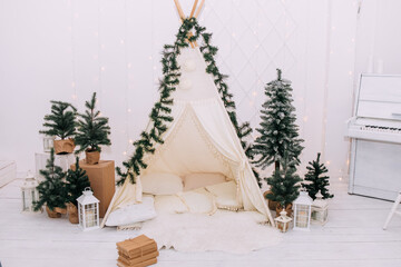 Christmas wigwam. Hall room with cozy atmosphere with Christmas trees and a lot of pillows in beige, gold and white colors. Сelebration of New Year. No people	
