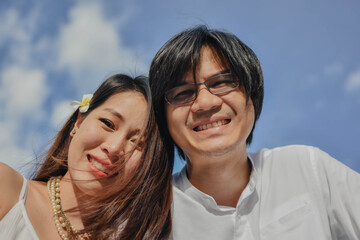 Asian couple looking at the camera with the blue sky