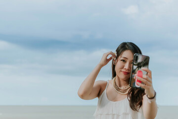 Beautiful asian woman taking selfie of herself on the beach