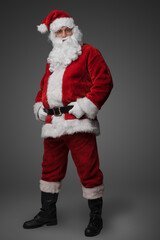 Studio shot of cheerful elderly santa dressed in red winter costume.