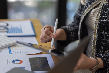 Asian Business woman using calculator and laptop for doing math finance on an office desk, tax, report, accounting, statistics, and analytical research concept