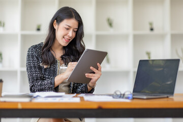 Fototapeta premium Asian Business woman using calculator and laptop for doing math finance on an office desk, tax, report, accounting, statistics, and analytical research concept