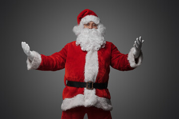Studio shot of friendly old santa with glasses and beard isolated on gray background.