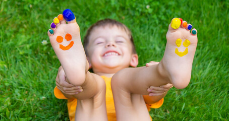 Children's feet with a pattern of paints smile on the green grass. Selective focus.