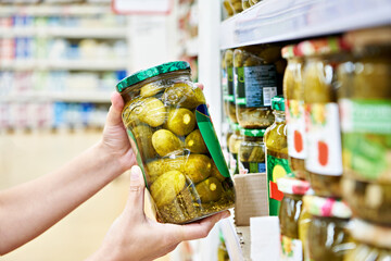 Pickled cucumbers in jar in hand