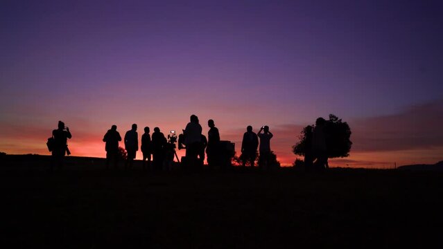Fast speed silhouette of a movie crew at sunset on location land field