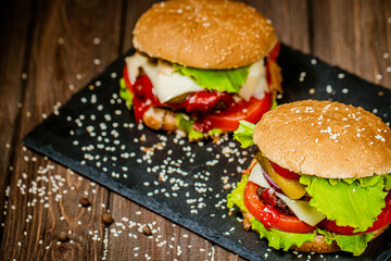 From above view of appetite burgers with beef, cheese, tomato, lettuce on board. Selective focus