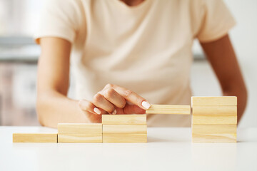 Woman hand arranging wood cube stacking as stair step shape