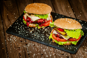 From above view of delicious burgers with beef, cheese, tomato, lettuce on board. Selective focus