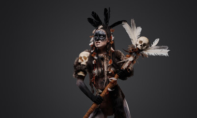 Shot of fearful necromancer with fur holding staff against grey background.