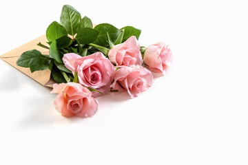 Pink roses in a paper envelope on a white background. Creative gift. Copy space. Photo