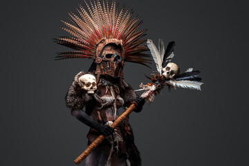 Studio shot of creepy aztec witch dressed in aboriginal attire with plumed headdress.