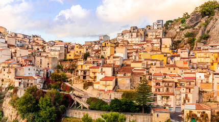 Obraz premium old mediterranean mountain dense town with levels of yellow houses and terraces on a steep mountain in evening light, vintage european village on a rock