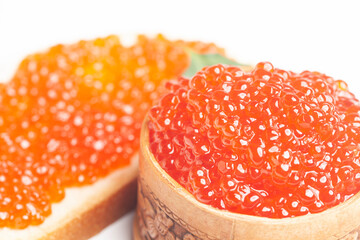 delicious red caviar in wooden bowl and sandwich with red caviar isolated on white background.