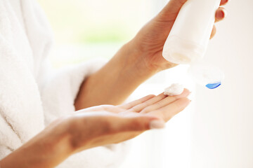 Woman applying organic cream on hands in bathroom