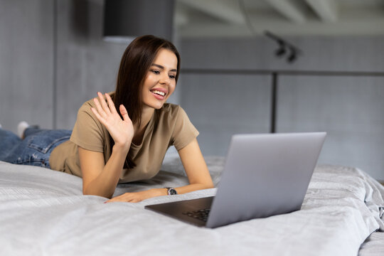 Young Woman Working Form Home With Laptop And Waving Hand On A Video Call