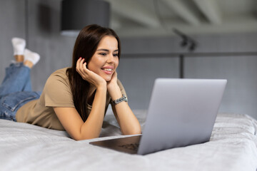 Beautiful woman lying in bed with a laptop at home