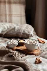 warm cozy bedroom interior with cup of hot chocolate on tray, candles