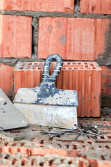 Construction trowel for laying bricks and blocks. Construction tool of a bricklayer. Hand working tool on the background of brickwork.