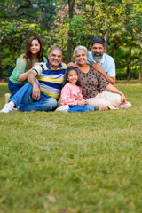 Fototapeta premium Happy indian or asian family sitting at park.