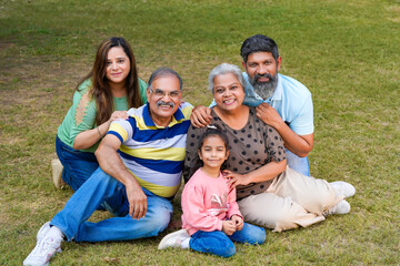 Fototapeta premium Happy indian or asian family sitting at park.